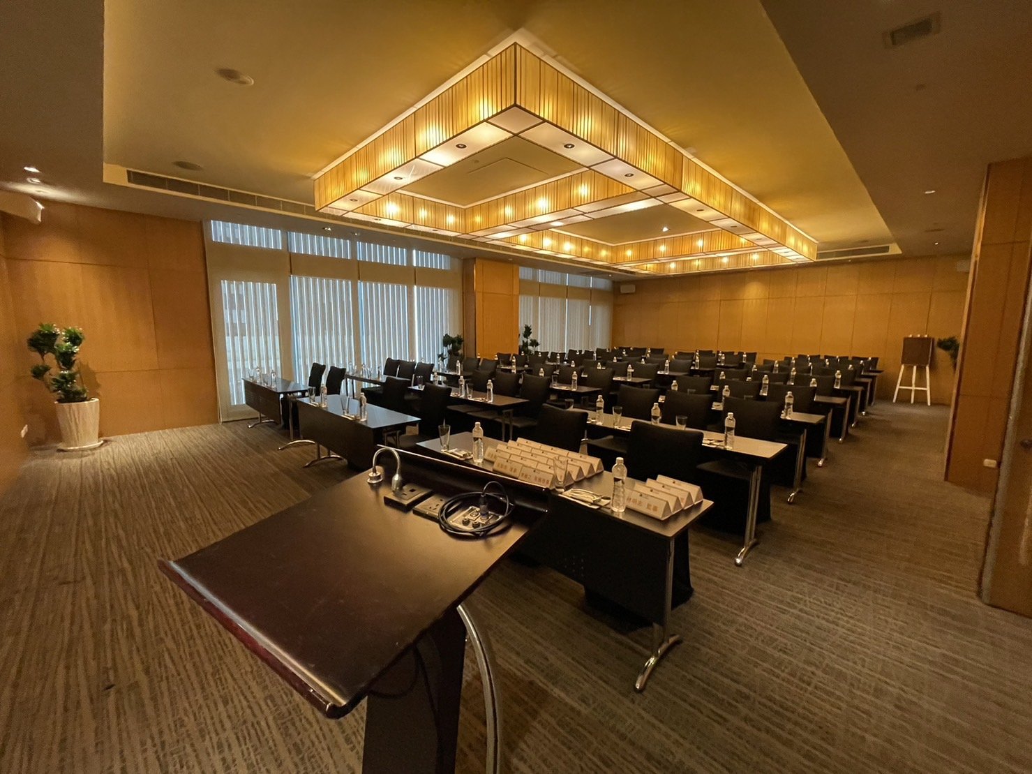 Meeting room VEE05 with rows of tables, a lectern, and a lit ceiling panel